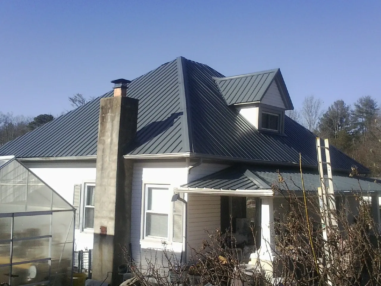 Dark blue standing seam metal roof on a white farmhouse with dormer — Slate & Tile Roof Repair by Roofing Brothers in Gerlach