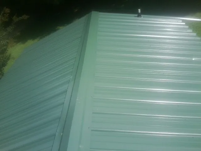New green metal panels meeting at the ridge of a roof — Flat Roof Repair work by our crew in Gerlach