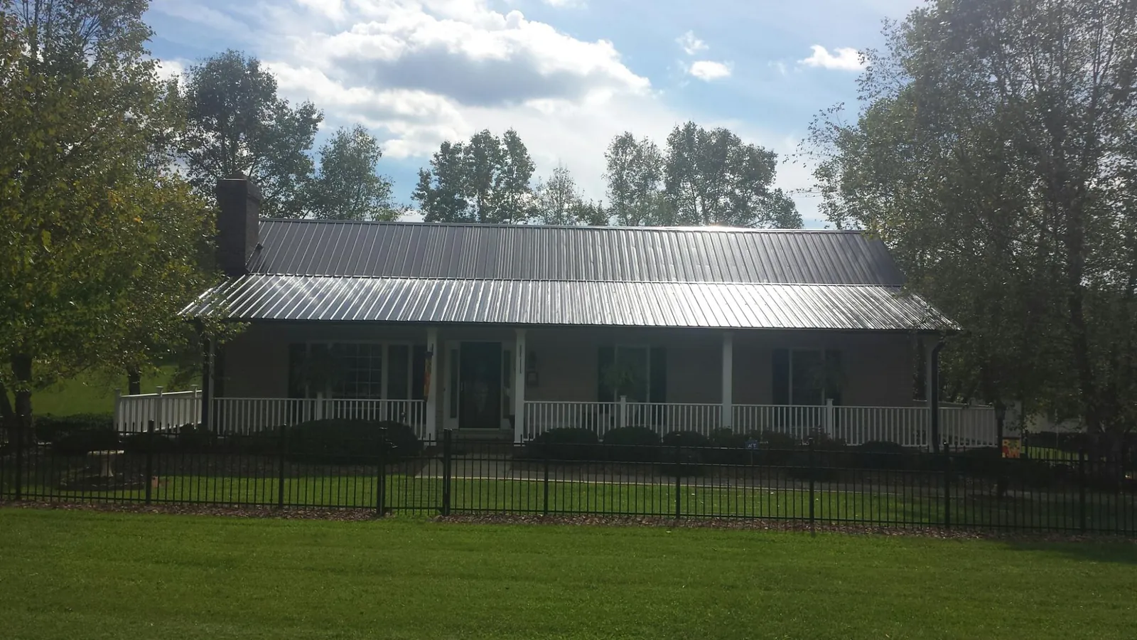 Gray metal roof on a brick ranch with a full width front porch — Gutter Guard Installation work by our crew in Gerlach