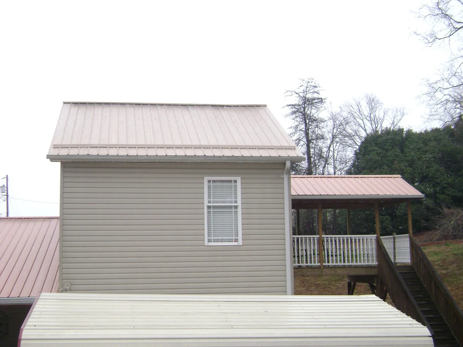 Tan metal roofs on a two story addition and attached porch, from a Roof Replacement job in Gerlach