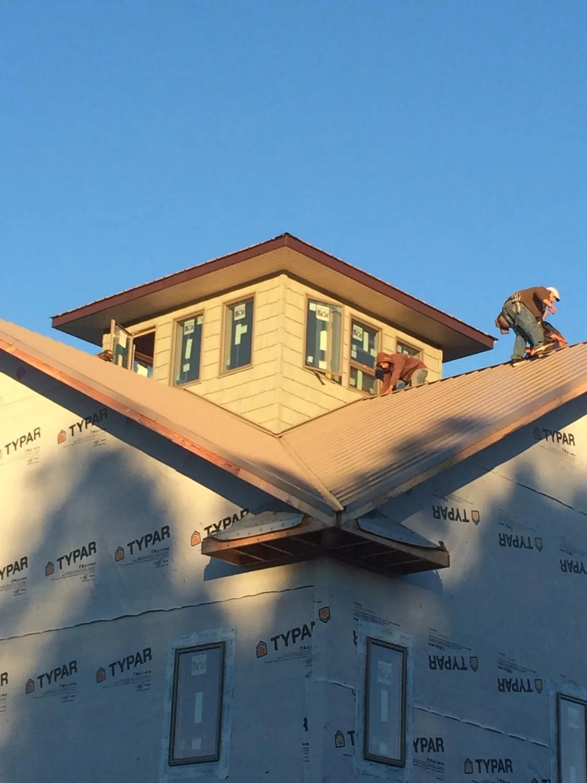 Roofers working around a rooftop cupola on a new metal roof at sunset — Roof Waterproofing in Gerlach by Roofing Brothers